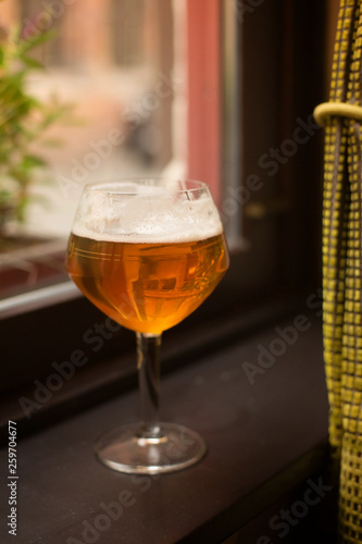 a glass with Belgian beer on the window