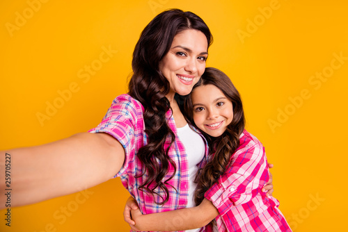 Close up photo two people funny brown haired mum mom small little daughter make take selfies daddy wait him his he home house miss wear casual pink checkered plaid shirts isolated yellow background