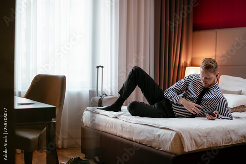 Businessman relaxing after meetings. Man checking his wifi connection at a hotel room. © JustLife