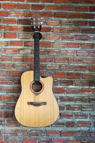 Acoustic guitar with brick wall background. © Jittima