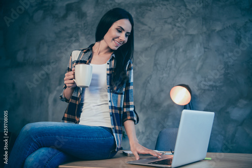 Portrait of nice cute attractive charming cheerful brunette lady wearing checked shirt free time browsing news video chat sitting on desk at industrial loft style interior work place station