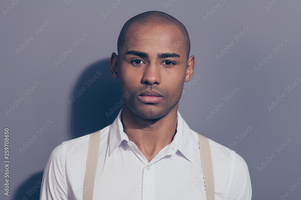 Obraz premium Close up photo beautiful amazing dark skin he him his man looking straight on camera kind sincere eyes shiny shaved face wearing white shirt pastel suspenders clothes isolated grey background