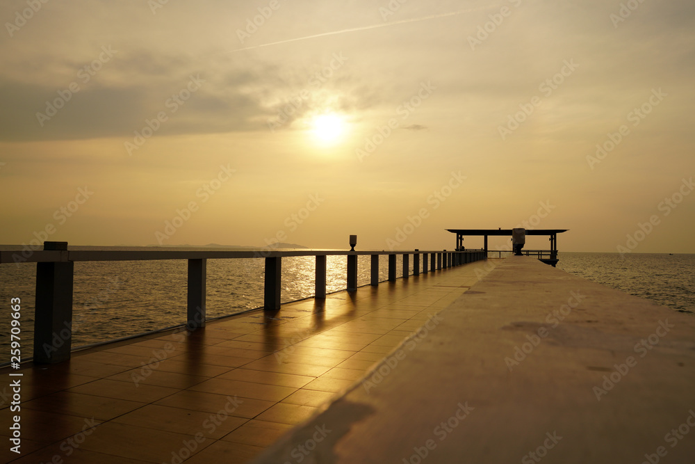 Wooded bridge in the port along sunrise at island beach.