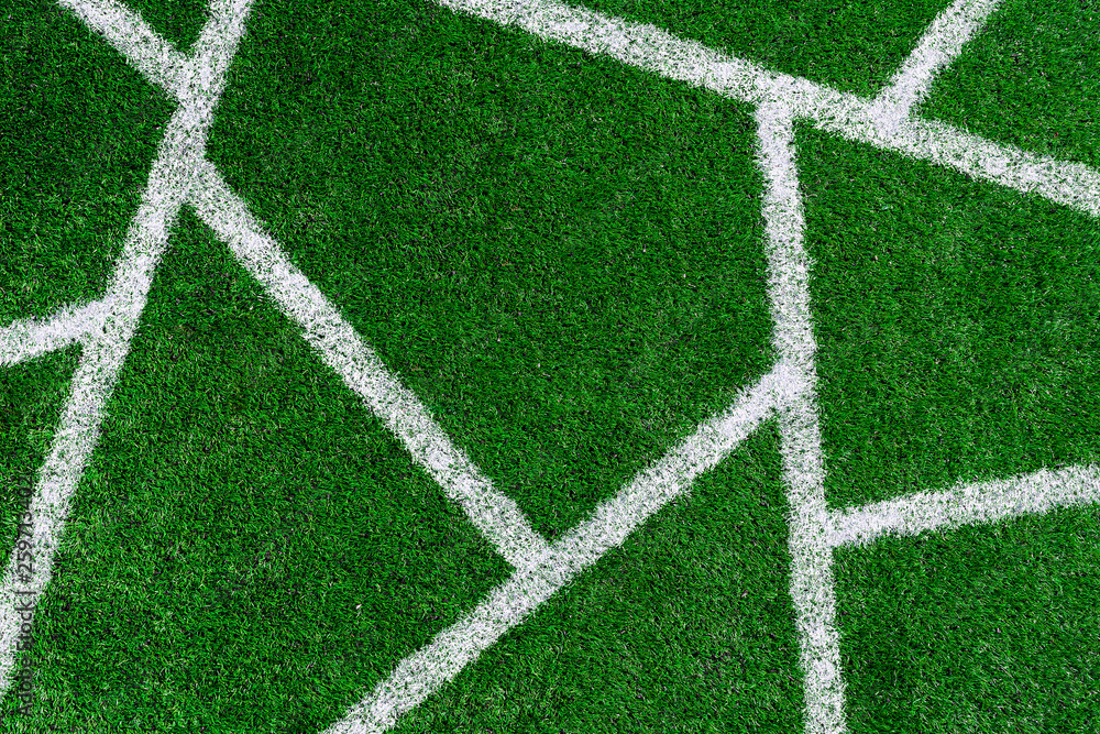 Fototapeta premium green grass on the football field with white non-parallel stripes on it