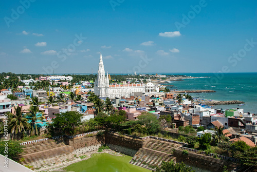 Our Lady of Ransom Shrine Church behind colorful houses on a sand beach occupied by fishing boats in Kanyakumari in India
