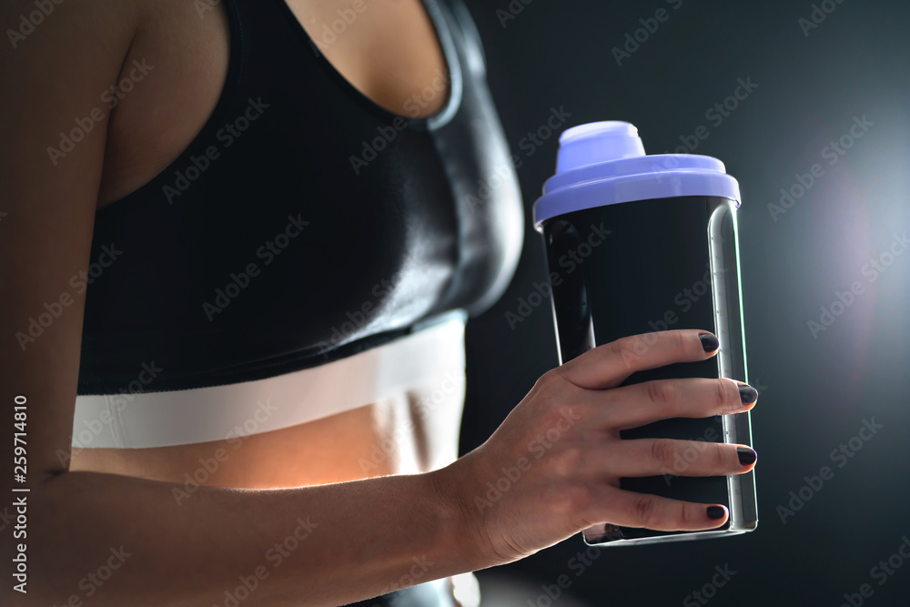 Protein shake after workout and gym training. Fit woman holding bottle
