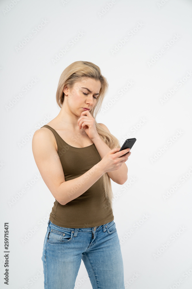 A young girl is thinking and looking at the phone. Isolated on white background A young girl is thinking and looking at the phone. Isolated on white background