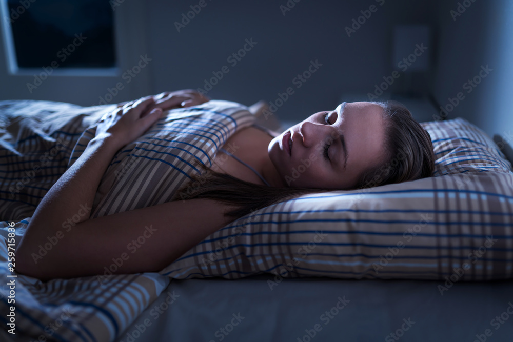 Calm and peaceful woman sleeping in bed in dark bedroom. Lady asleep at  home in the middle of the night. Pillow, blanket and moonlight. Nightmare  or sleep apnea concept. Photos