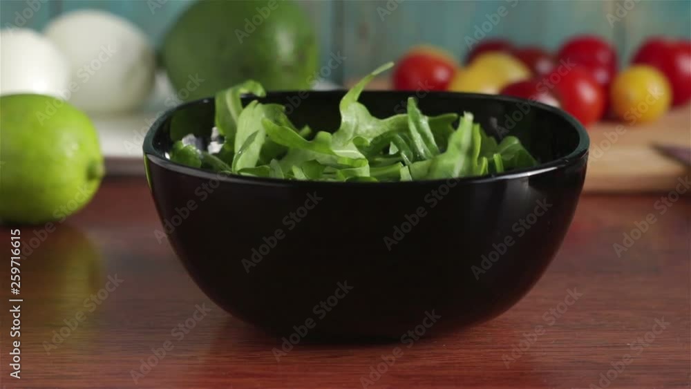 put cherry tomatoes halves in to bowl with arugula salad leaves put cherry tomatoes halves in to bowl with arugula salad leaves