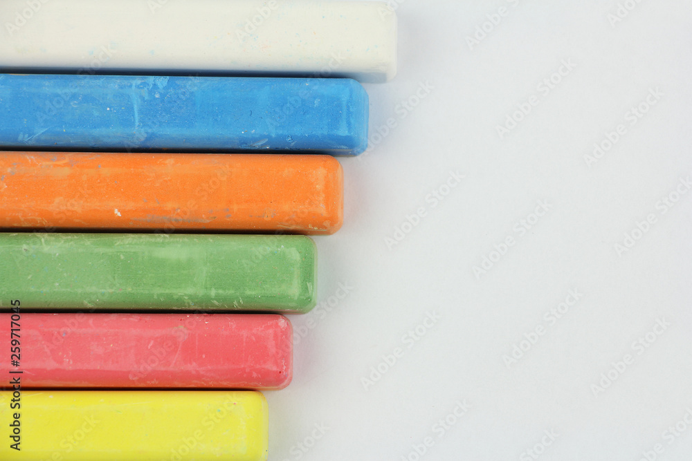 six colored children crayons on white background, on left side, blue red green yellow orange white, top view six colored children crayons on white background, on left side, blue red green yellow orange white, top view
