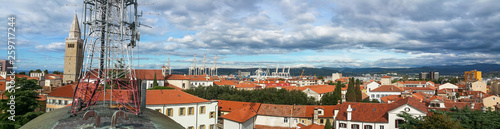 Panoramic view from the roof with cellular network antenna tower on top transmitting mobile signal over old city town Koper, Slovenia covered with black clouds