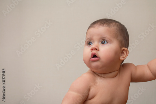 Baby 9 months looking away with open mouth and surprised eyes, portrait, indoors, copyspase