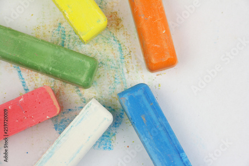 colored children crayons scattered on white paper, top view, copy space