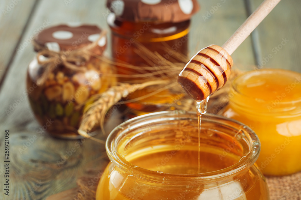 Honey background. Sweet honey in glass jar on wooden background. Honey background. Sweet honey in glass jar on wooden background.