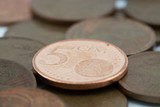 Five euro cent coin supported on more bronze coins.