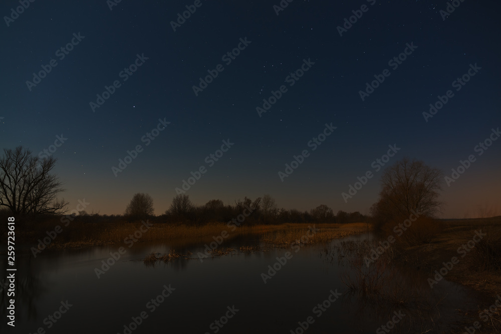 Fototapeta premium Stars in the night sky over the river. Early spring in central Russia.