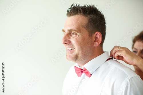 Handsome man prepared for wedding, girl fixing his bow tie