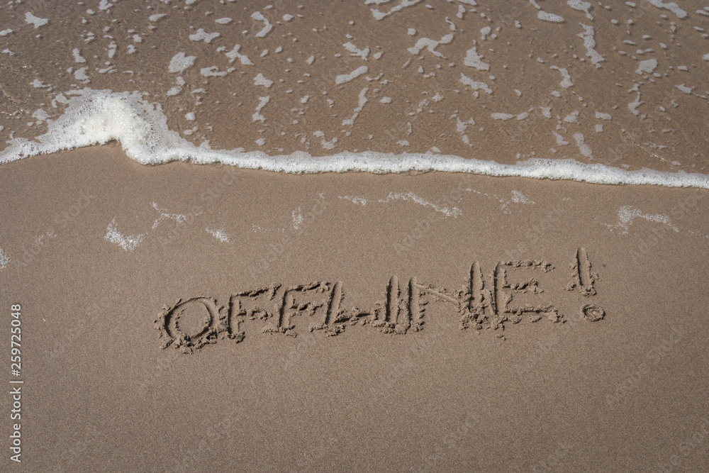 Fototapeta premium The word “offline” written in the sand symbolizing a time-out