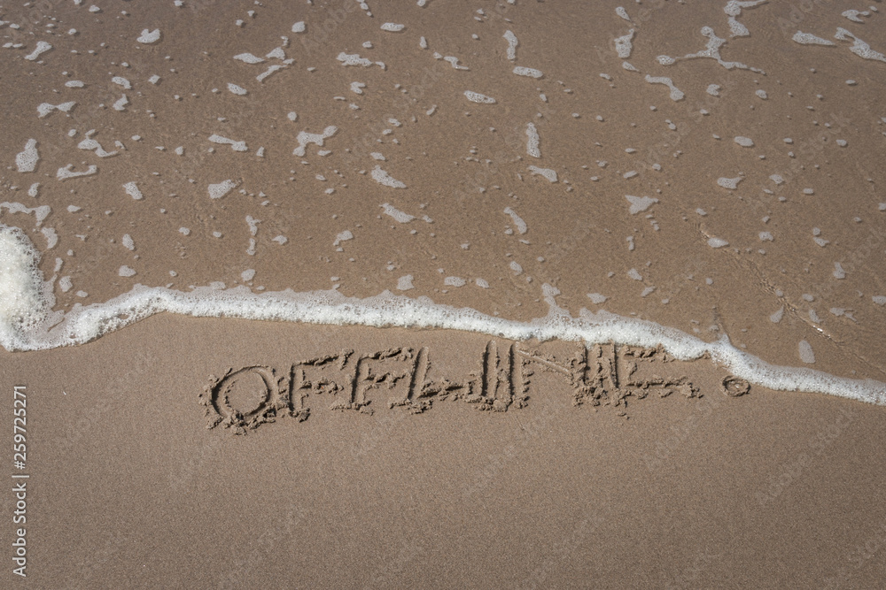 Fototapeta premium The word “offline” written in the sand symbolizing a time-out