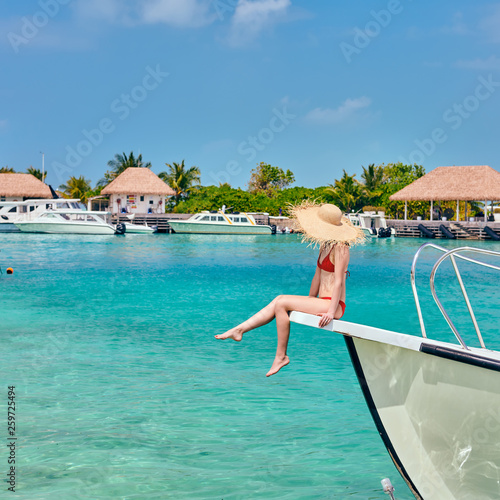 Woman in red bikini sitting on boat bow