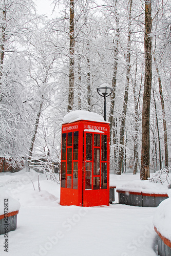 Red British telephone booth used as street library in winter (translated from Russian "Library") © yulyao