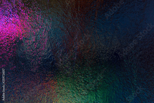 Water flow on glass with colored light show from behind