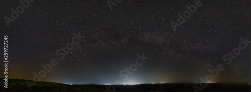 Stars of the Milky Way in the night sky. Light pollution from street lamps above the horizon.