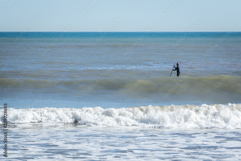 Surfer with paddle board catching the wave