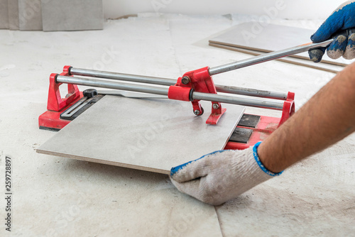 Fotografie Tiler cutting tiles with tile cutter