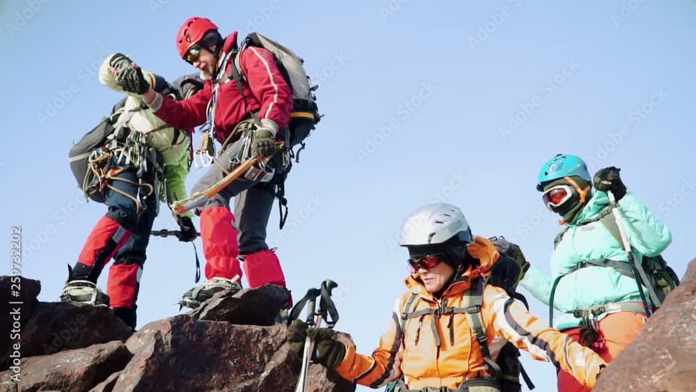 climbers in equipment slowly down one after another from the rock, helping each other. they are dressed with special gear, protective masks and mountain sticks. climbers in equipment slowly down one after another from the rock, helping each other. they are dressed with special gear, protective masks and mountain sticks.
