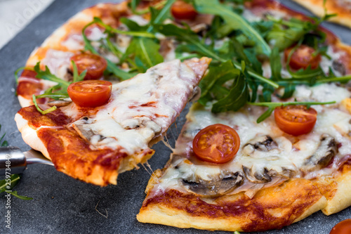 Sliced pizza with arugula and cherry tomatoes.