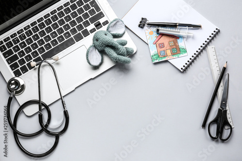 Laptop, stethoscope, stationery and toy on light background