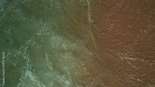 Aerial; view from above; drone shot of crushing wave; white foam, drops of seawater; top down view of emerald water in Portugal; Huge ocean wave during storm, sea water background in rough conditions