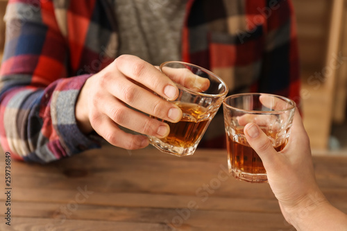 Man and woman clinking glasses of cold whisky  closeup