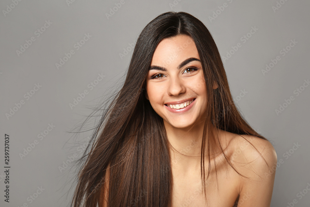 Portrait of beautiful young woman with healthy long hair on grey background - obrazy, fototapety, plakaty 