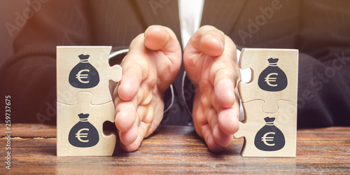 Obraz na plátně Businessman separates the wooden puzzle with a picture of money
