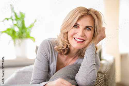 Portrait einer attraktiven älteren Frau zuhause auf der Couch, best ager 