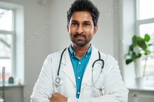 Indian doctor with stethoscope around neck in his office