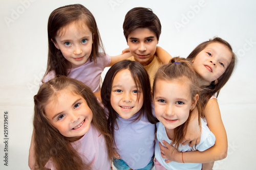 The portrait of happy cute little kids boy and girls in stylish casual clothes looking at camera against white studio wall. Kids fashion and human emotions concept © master1305
