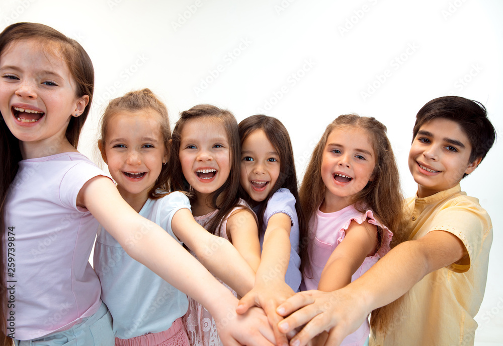 The portrait of happy cute little kids boy and girls in stylish casual clothes looking at camera against white studio wall. Kids fashion and human emotions concept The portrait of happy cute little kids boy and girls in stylish casual clothes looking at camera against white studio wall. Kids fashion and human emotions concept