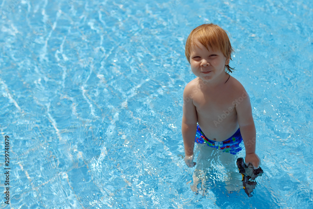 Blond-haired toddler standing in the swimming pool