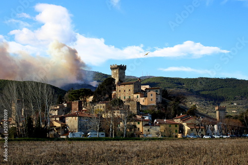 the medieval village of Vicopisano with the Pisan mountains on fire 