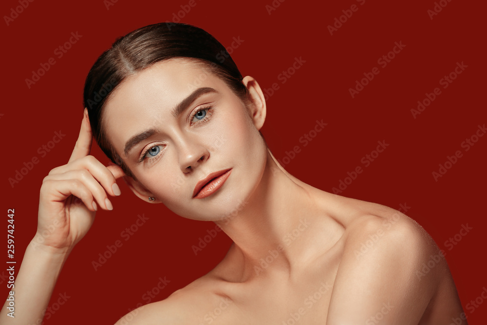 A beautiful female face. Perfect and clean skin of young caucasian woman on red studio background. A beautiful female face. Perfect and clean skin of young caucasian woman on red studio background.
