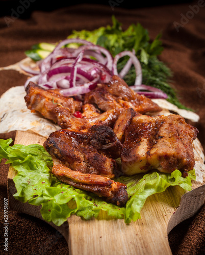 grilled barbecue meat served on a wooden Board with fresh vegetables and spices