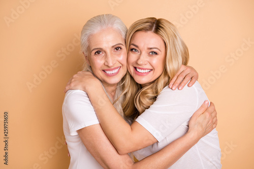 Close-up portrait of nice sweet lovely attractive charming cheerful cheery dreamy ladies wearing white t-shirt cuddling spending time isolated on beige pastel background
