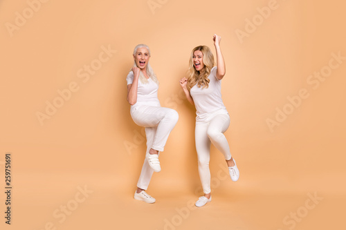 Full length body size view portrait of nice cool attractive charming slender slim fit cheerful cheery ecstatic ladies wearing white t-shirt having fun isolated on beige pastel background