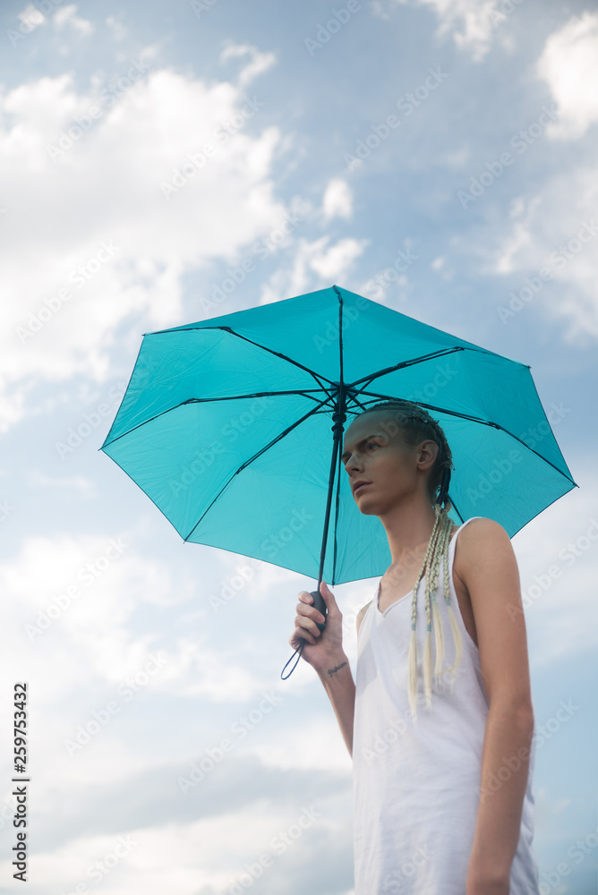 Young man with braided hair holding umbrella