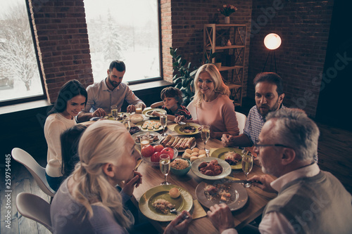 Close up photo big large family thanksgiving conversation members company brother sister granny mom dad grandpa son daughter sitting round festive holiday full tasty dishes table loft house indoors