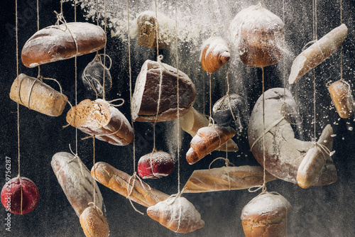 flour falling at loaves of white and brown bread and pastry hanging on ropes photo