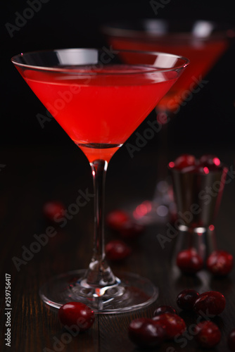 Cosmopolitan cocktail with cranberries and jigger. Dark wooden background, high resolution